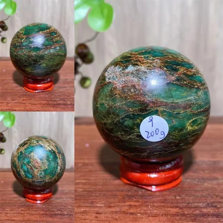 Verdite sphere with deep forest green and shimmering gold veins, displayed on a reddish-brown wooden stand.