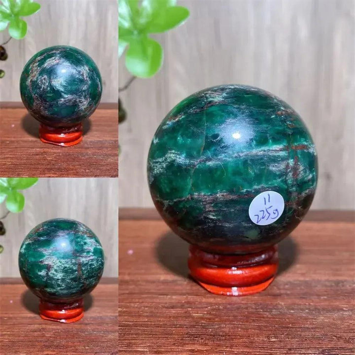 Polished Verdite sphere with deep forest green and shimmering gold veins on a reddish-brown wooden stand.