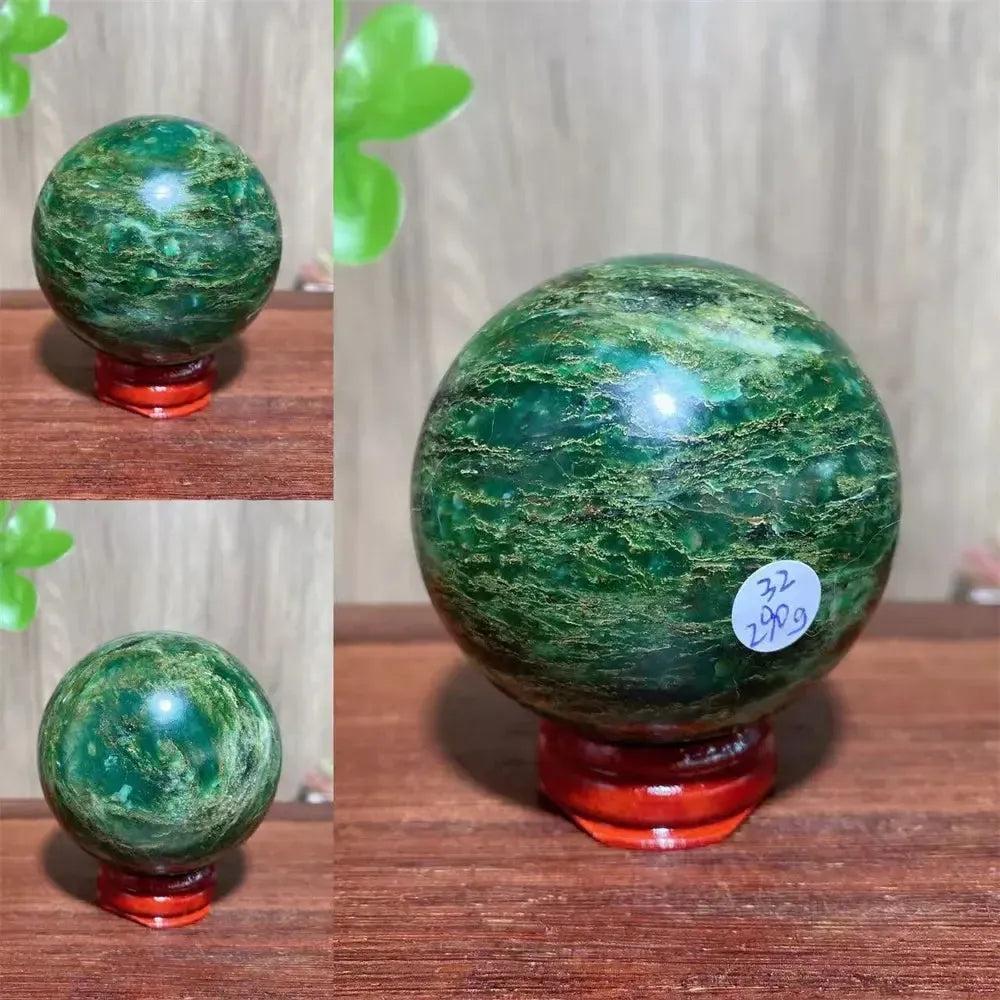 Polished Verdite sphere with deep forest green hues and shimmering gold veins, displayed on a red wooden stand.