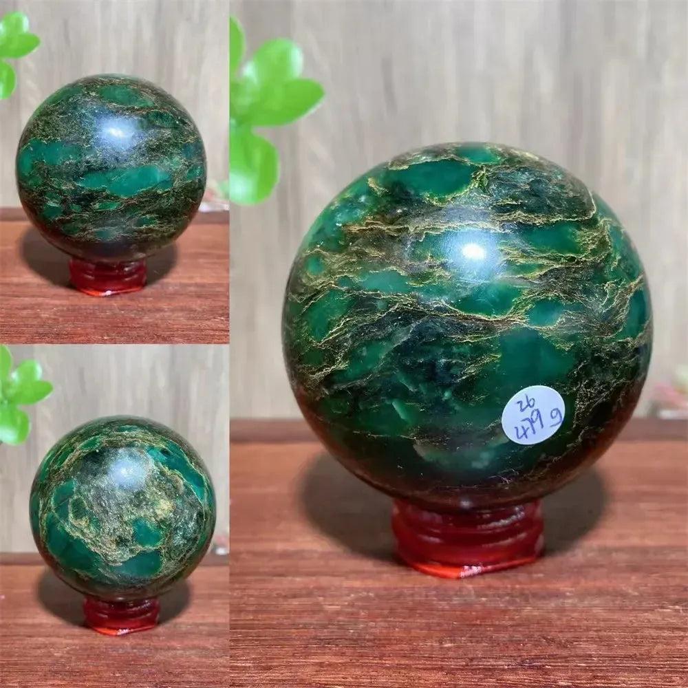 Verdite sphere with deep forest green and shimmering gold veins, on a red display stand.