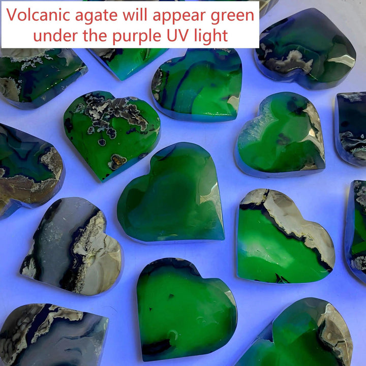 Heart-shaped volcanic agate stones, some bright green under UV light, others natural gray and black.