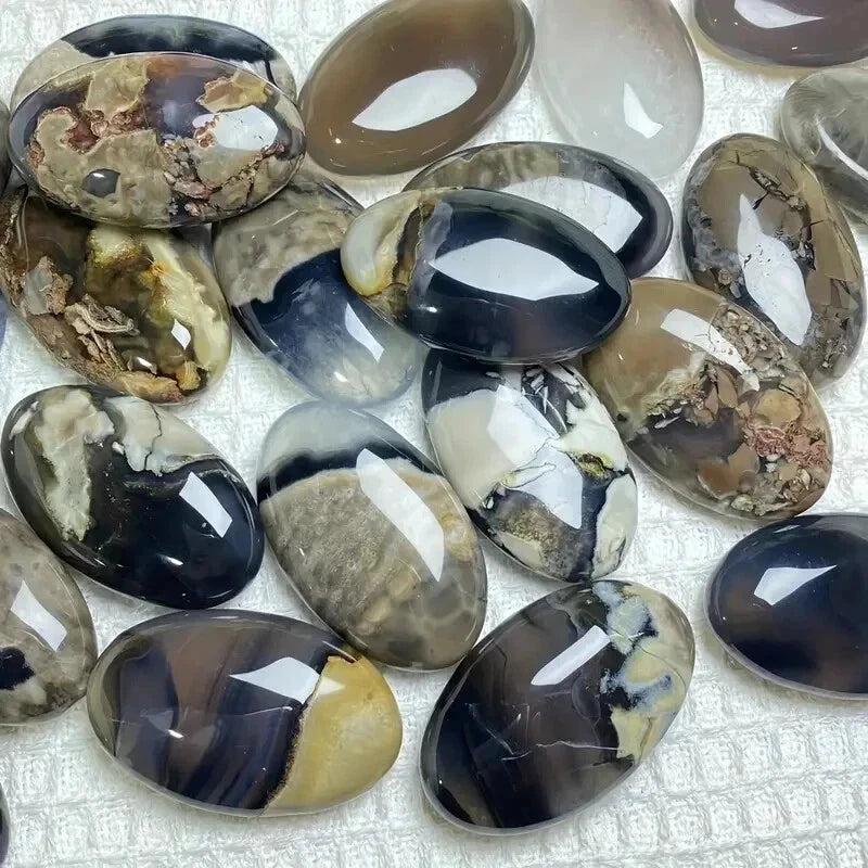 Polished natural volcanic agate palm stones in various earthy tones, some with white and black patterns.
