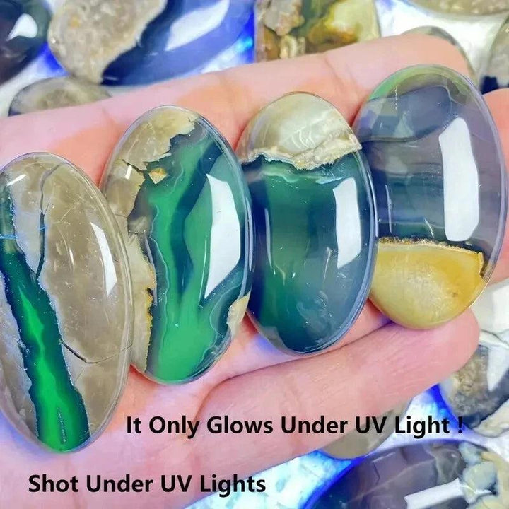 Four polished natural volcanic agate palm stones with green and brown hues, glowing under UV light.