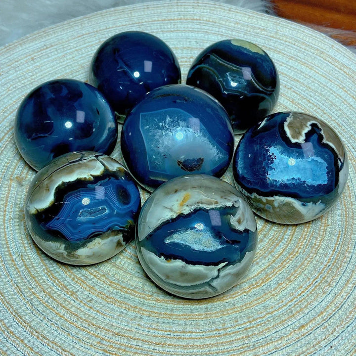 Volcanic Agate Spheres: UV Reactive Crystal Balls with rich blue, brown, and white banding, showcasing unique geological fingerprints.