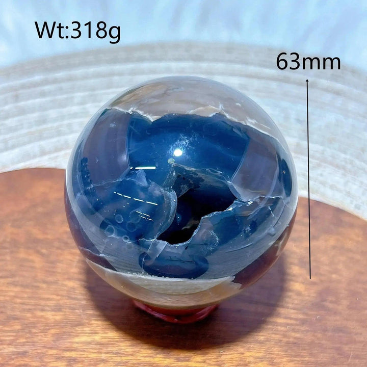Volcanic Agate Sphere, 63mm, 318g. A hand-polished, earthy sphere with a deep blue geode cavity, grounding and transformative.