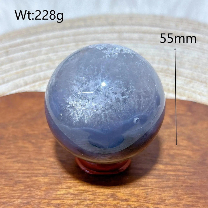 Volcanic Agate Sphere, a 55mm, 228g UV reactive crystal ball with deep blue and white banding, on a wooden stand.