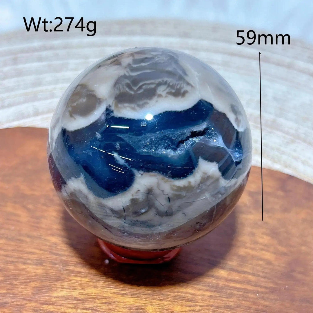 Volcanic Agate Sphere, 59mm, 274g. Earthy brown, white, and deep blue bands with a raw geode cavity. Grounding and transformative.