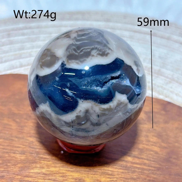 Volcanic Agate Sphere, 59mm, 274g. Earthy brown, white, and deep blue bands with a raw geode cavity. Grounding and transformative.