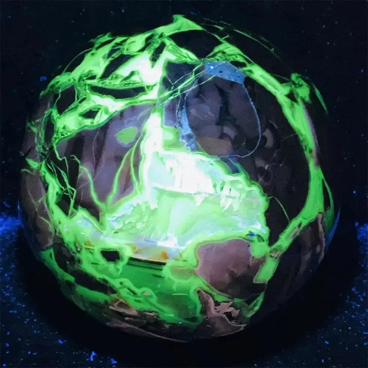 UV Reactive Volcanic Rock Agate Sphere glowing brilliantly with fluorescent green under blacklight.