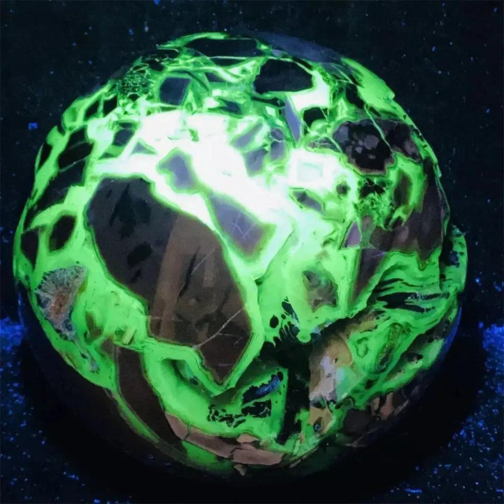 UV Reactive Volcanic Rock Agate Sphere glowing brilliant neon green under blacklight, revealing hidden depths.