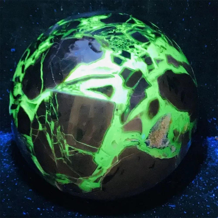 UV Reactive Volcanic Rock Agate Sphere glowing brilliant fluorescent green under blacklight.
