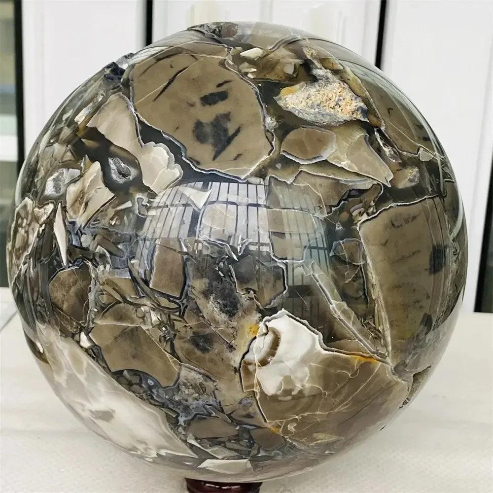 Polished UV Reactive Volcanic Rock Agate Sphere with earthy brown, black, and white patterns.