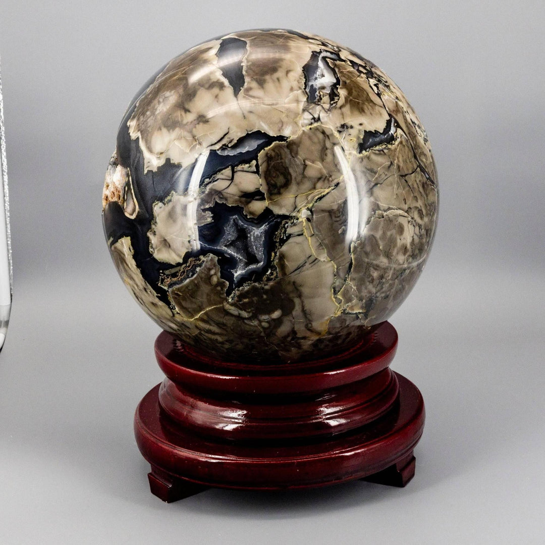 Volcano Agate Sphere XXL: 47lb polished crystal sphere with earthy rust, cream, deep brown, and ochre volcanic banding on a wood stand.