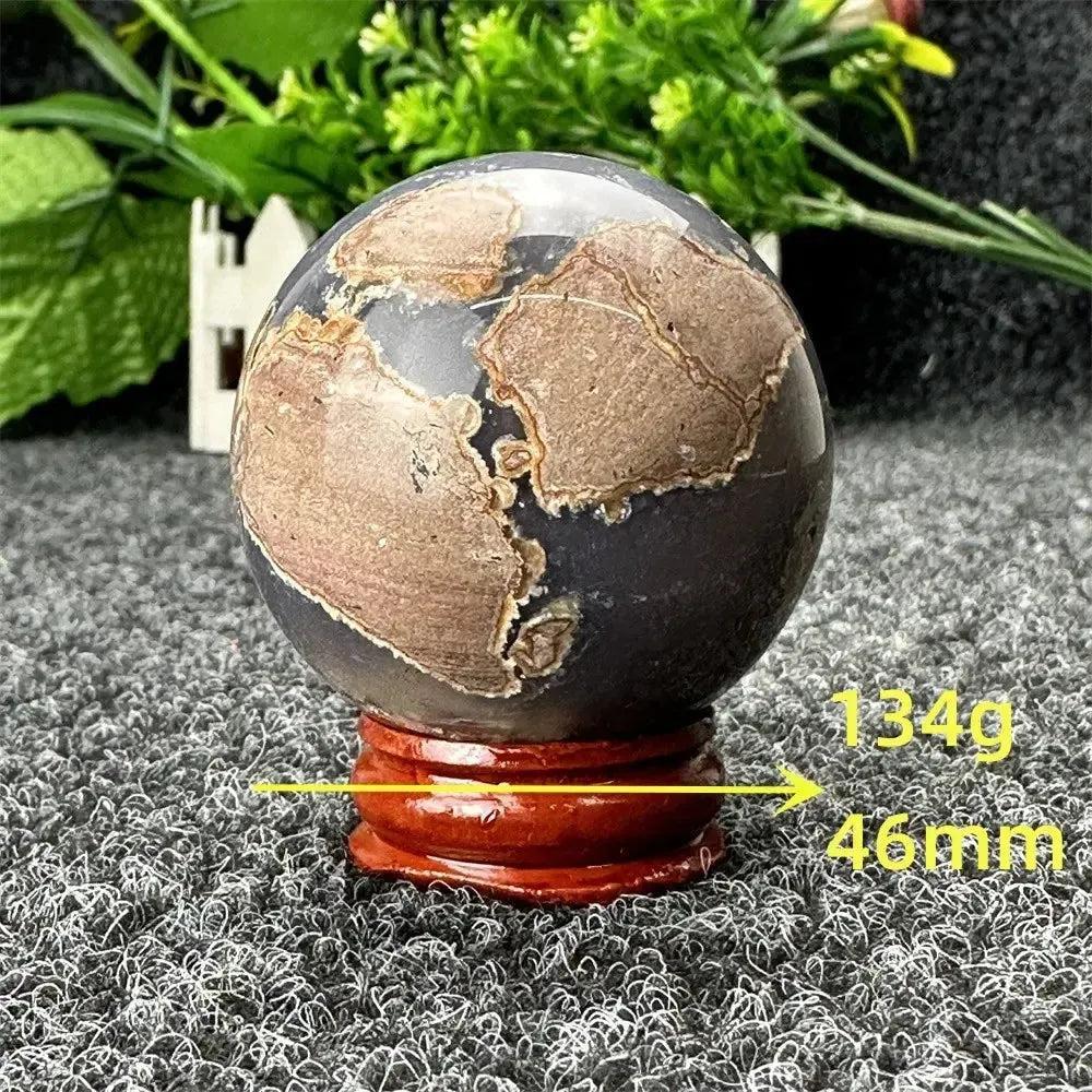 Volcano Agate sphere by Crystal Destiny, 46mm, 134g, with dramatic brown and gray patterns on a wooden stand.