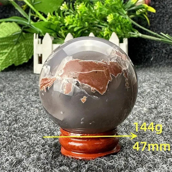 Volcano Agate sphere, 144g, 47mm, with fiery earth tones and dramatic patterns on a wooden stand from Crystal Destiny.