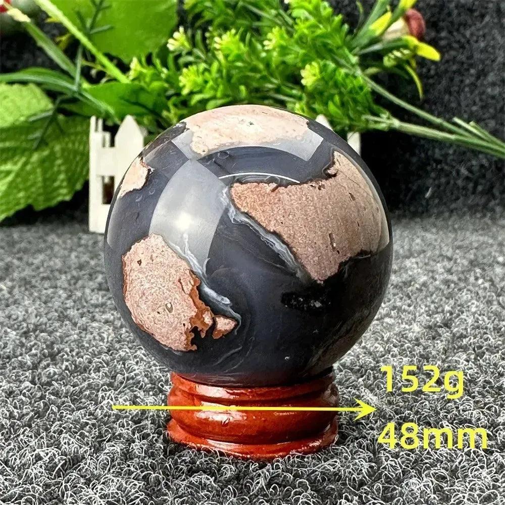 Polished Volcano Agate sphere, 152g, 48mm, with fiery earth tones and dramatic patterns on a wooden stand from Crystal Destiny.