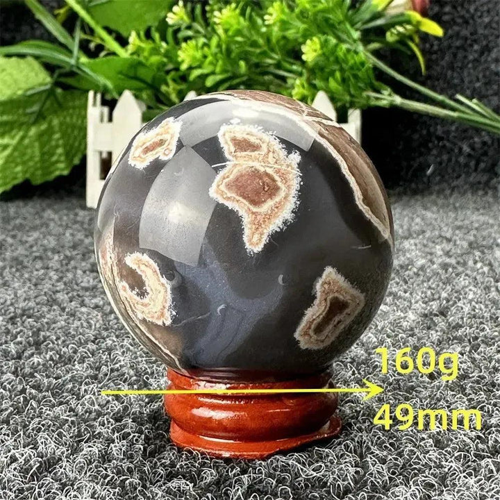 Polished Volcano Agate sphere from Crystal Destiny, 160g, 49mm, with fiery earth tones and dramatic patterns on a wooden stand.