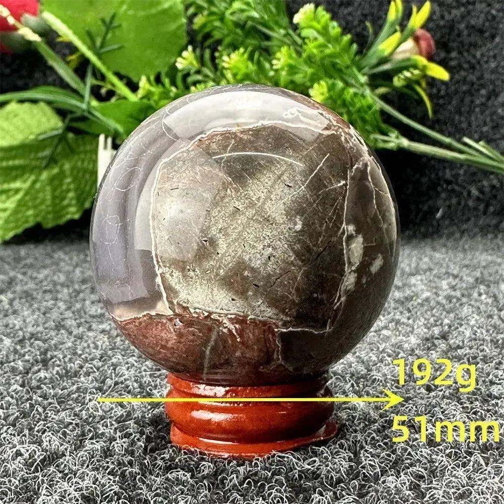 Volcano Agate sphere by Crystal Destiny, 51mm, 192g, with dramatic brown, red, and amber patterns on a wooden stand.