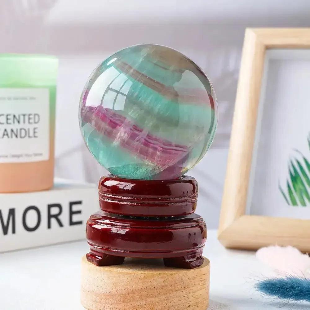 Watermelon Fluorite Crystal Sphere: vibrant green, lavender, and pink crystal ball on a polished wooden stand for clarity and focus.