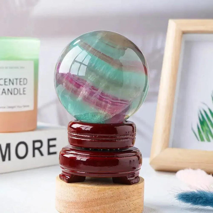 Watermelon Fluorite Crystal Sphere: vibrant green, lavender, and pink crystal ball on a polished wooden stand for clarity and focus.