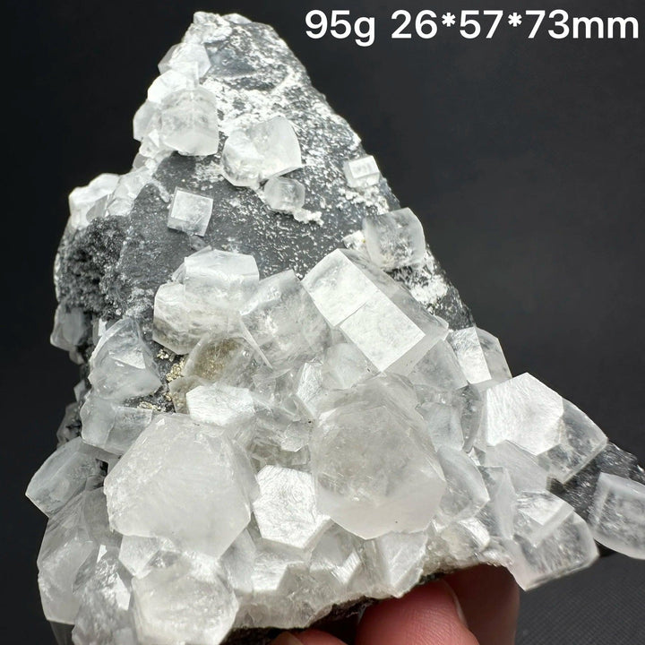 Raw white calcite crystal cluster specimen with cubic healing stones on a dark matrix.