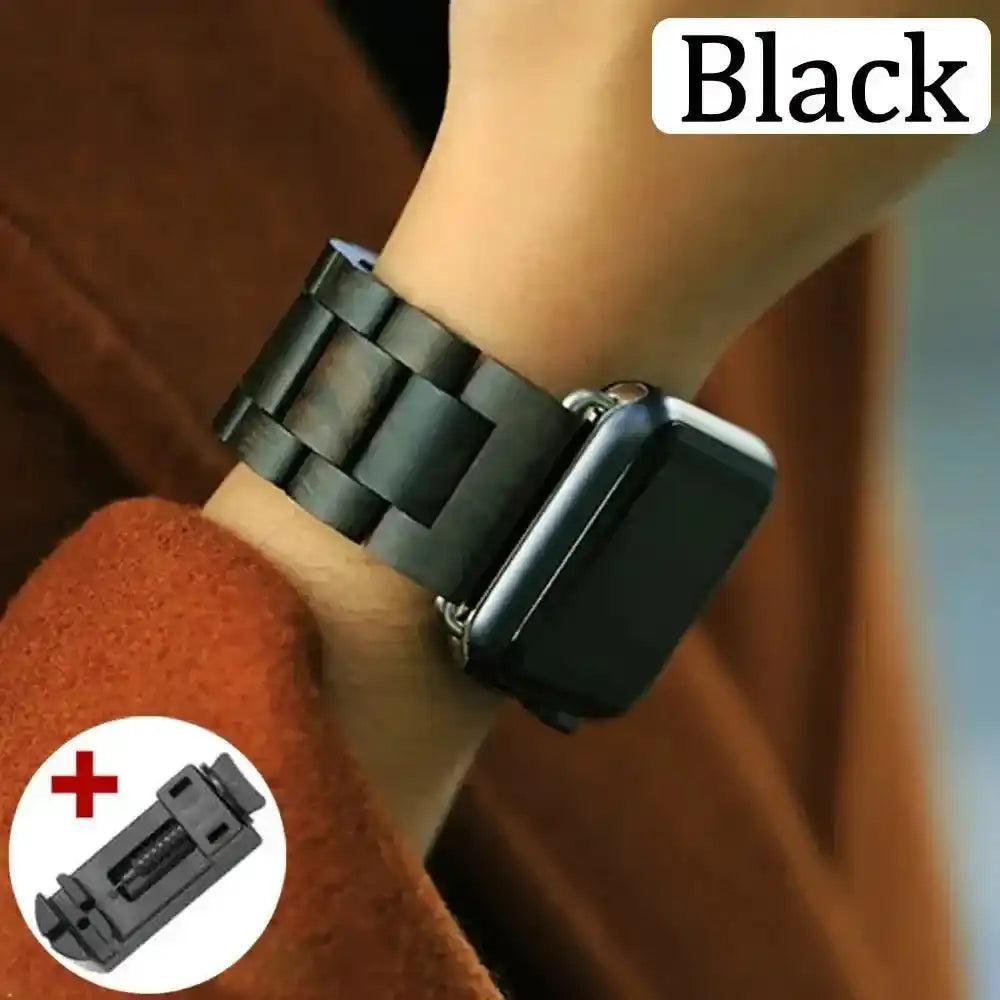 Handcrafted black wooden Apple Watch band with a link removal tool, worn on a wrist.