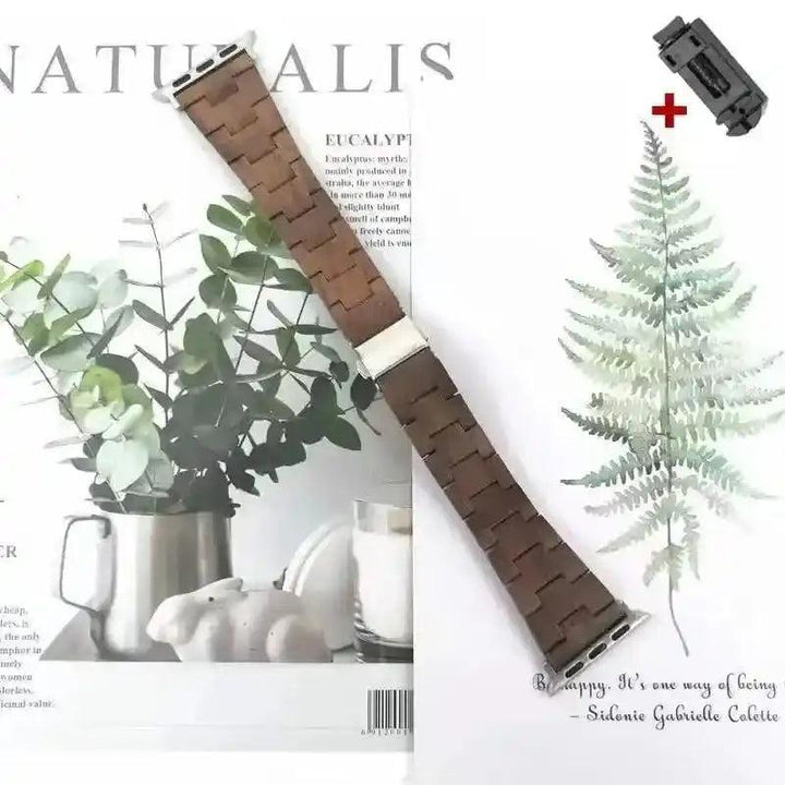 Handcrafted dark brown wooden Apple Watch band with silver-tone clasp, displayed on a nature-themed background.