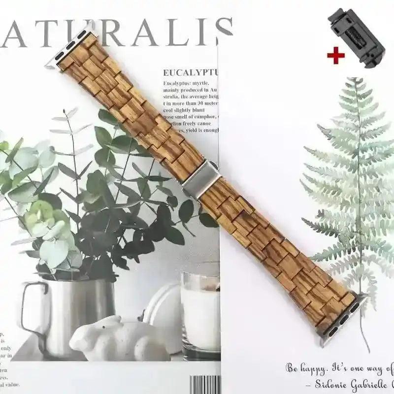 Handcrafted wooden Apple Watch band with natural wood grain, silver clasp, and link removal tool, on a botanical background.