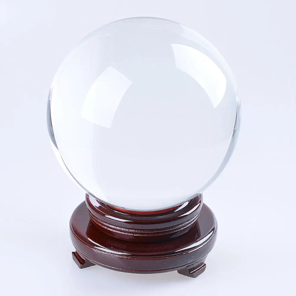 Clear crystal ball on a dark brown, natural wood display stand base, perfect for grounding and clarity.