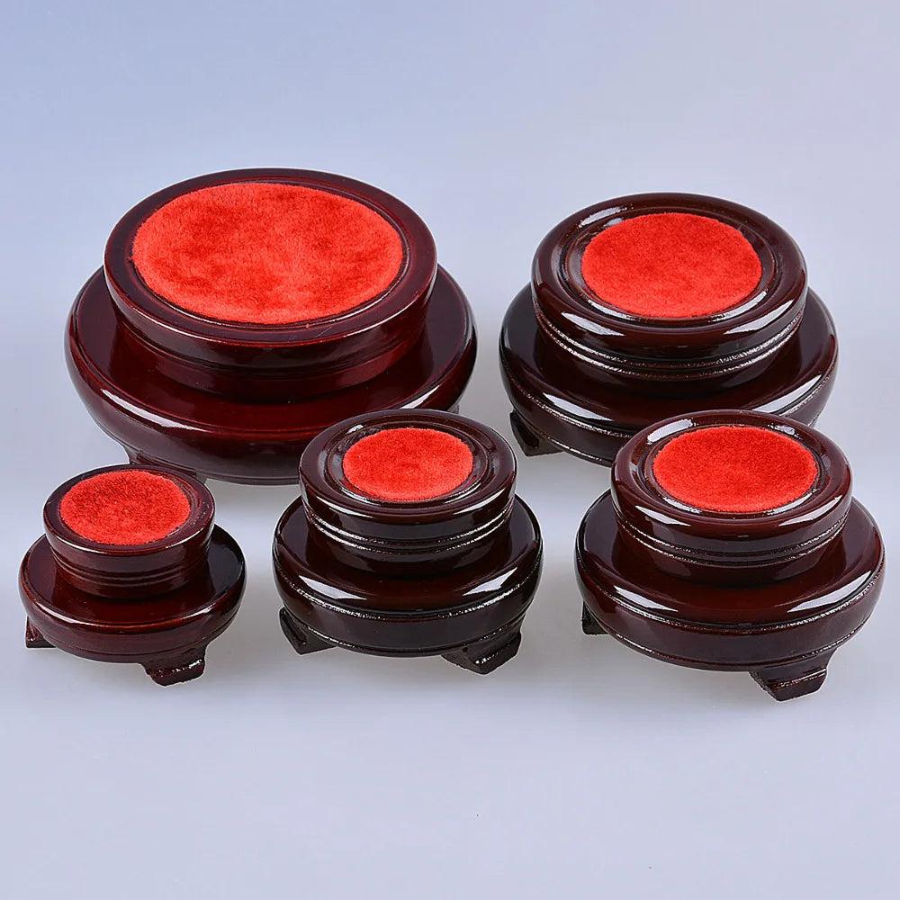 Set of five dark wood crystal ball display stands with red velvet tops, varying in size.