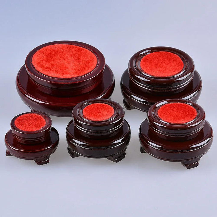 Set of five dark wood crystal ball display stands with red velvet tops, varying in size.