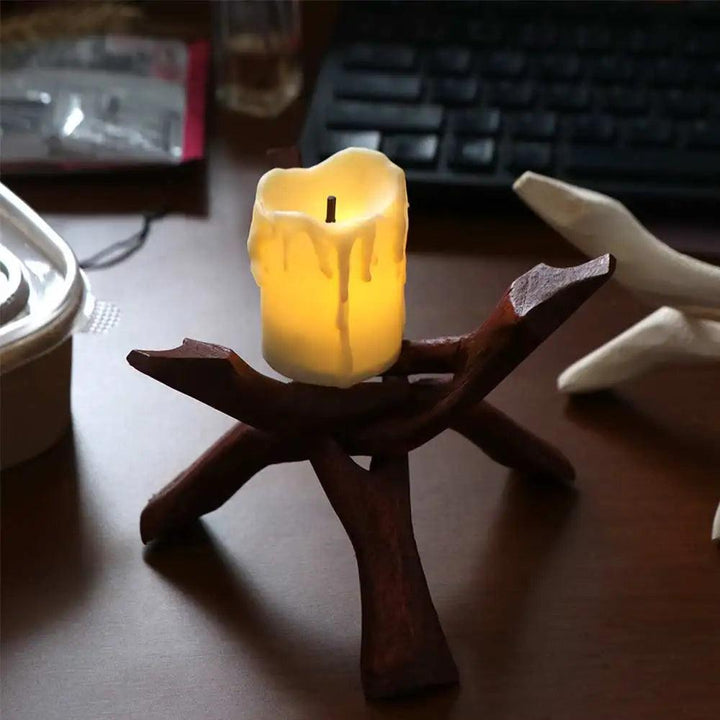 Dark wood tripod stand holding a glowing white LED candle, with a natural, organic finish.