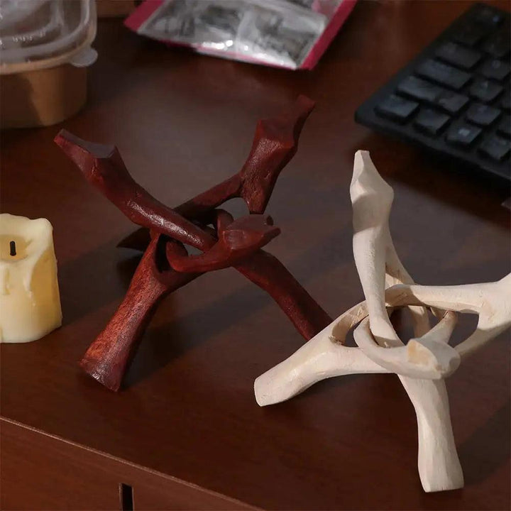 Two wooden tripod display stands, one dark brown and one light natural wood, on a desk.