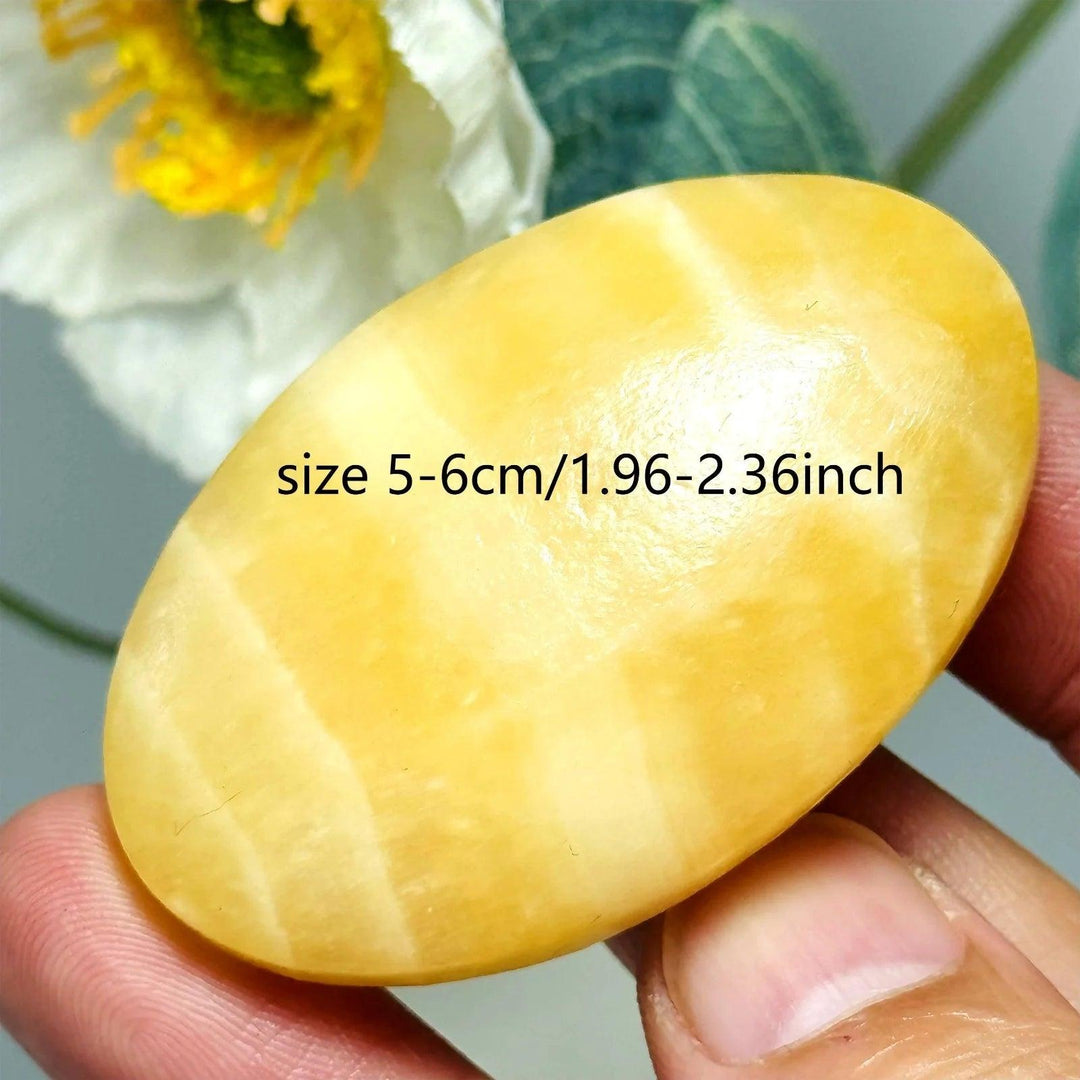 Smooth yellow calcite palm stone, a polished oval crystal for healing and meditation.