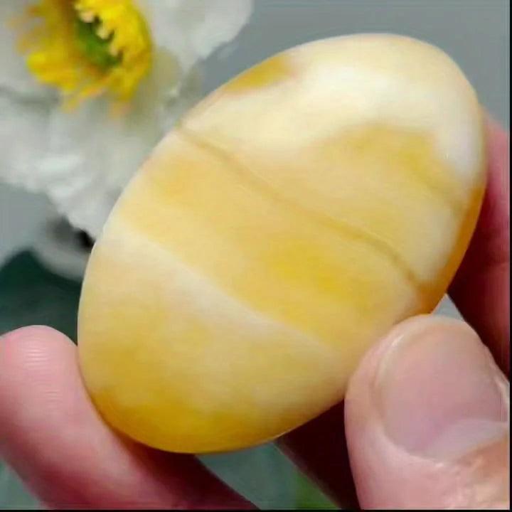 Smooth yellow calcite crystal palm stone held in hand, perfect for meditation and home decor.