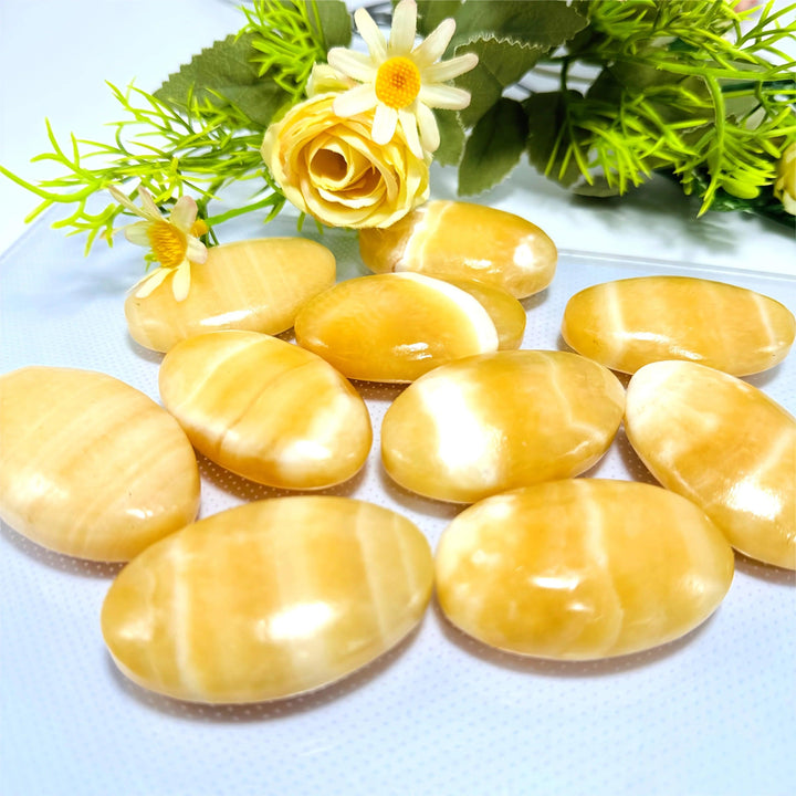 Smooth, polished yellow calcite palm stones with healing energy, perfect for home decor and meditation.