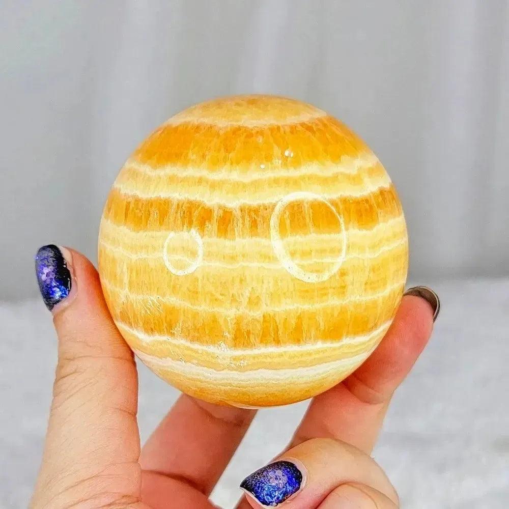 Polished Yellow Calcite Honey Calcite Sphere with warm honey-golden tones, natural banding, and striations.