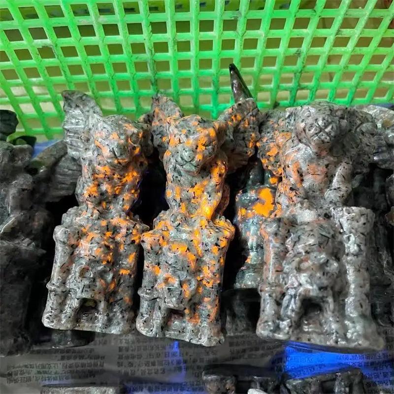UV-reactive Yooperlite gargoyle statues, dark gray with vivid orange glow, in a green basket.