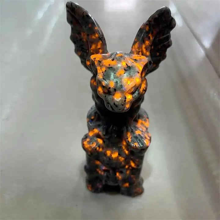 UV reactive Yooperlite gargoyle statue, glowing vivid orange and gold, for protection and intuition.