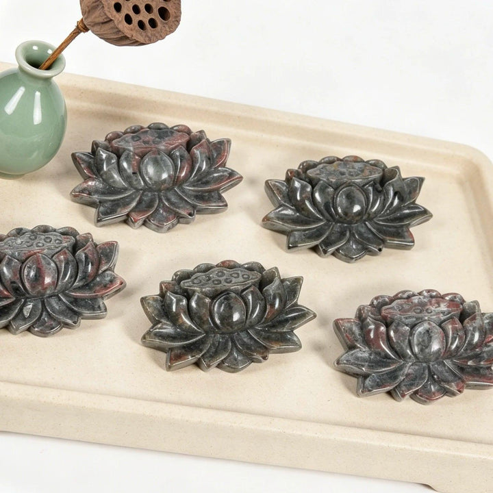 Five hand-carved Yooperlite lotus flower statues, detailed grey stone with red flecks, symbolizing peace and manifestation.