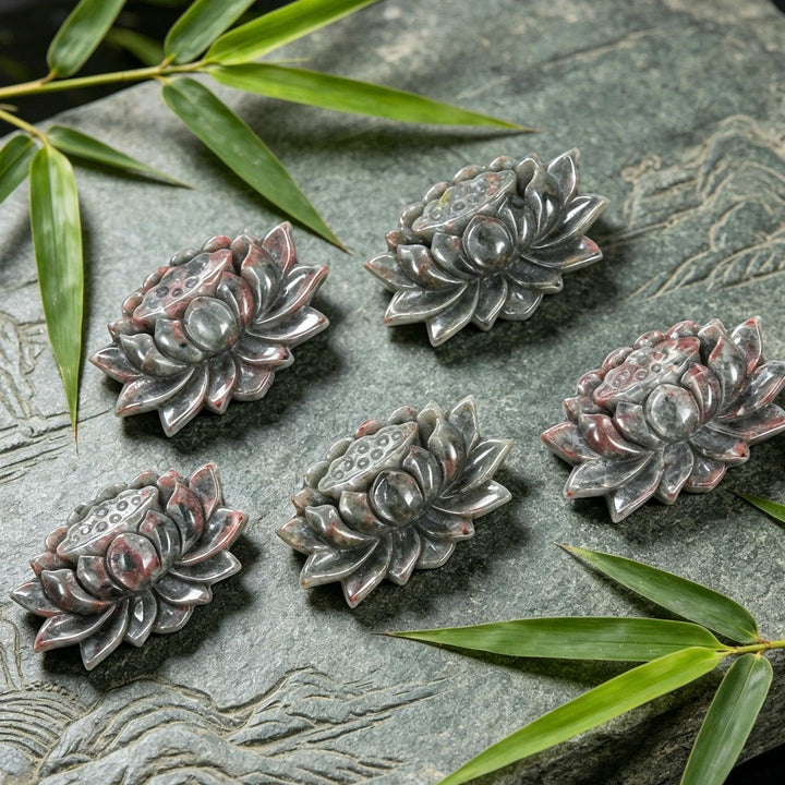 Five hand-carved Yooperlite lotus flower statues, detailed grey stone with red accents, symbolizing peace and tranquility.