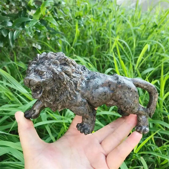 Hand-carved Yooperlite lion statue with a polished grey-green finish, glowing orange-yellow under UV light.