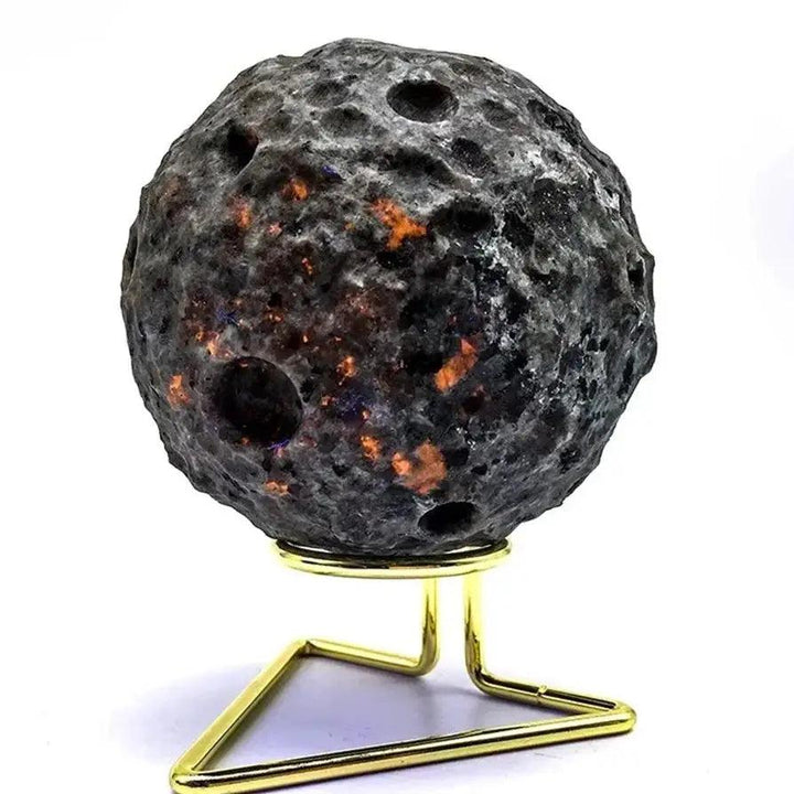 Textured Yooperlite moon sphere with glowing orange inclusions on a gold stand for Reiki healing and spiritual decor.