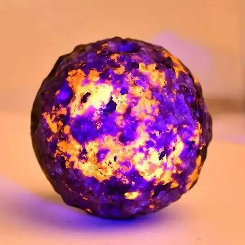 Glowing Yooperlite crystal moon sphere with vibrant orange and purple patterns for Reiki healing and spiritual energy.