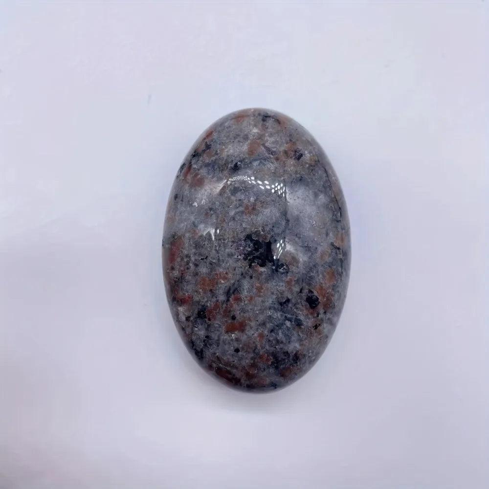 Yooperlite Crystal Palm Stone, a smooth, grounding grey stone with subtle flame-like patterning, for stability and protection.