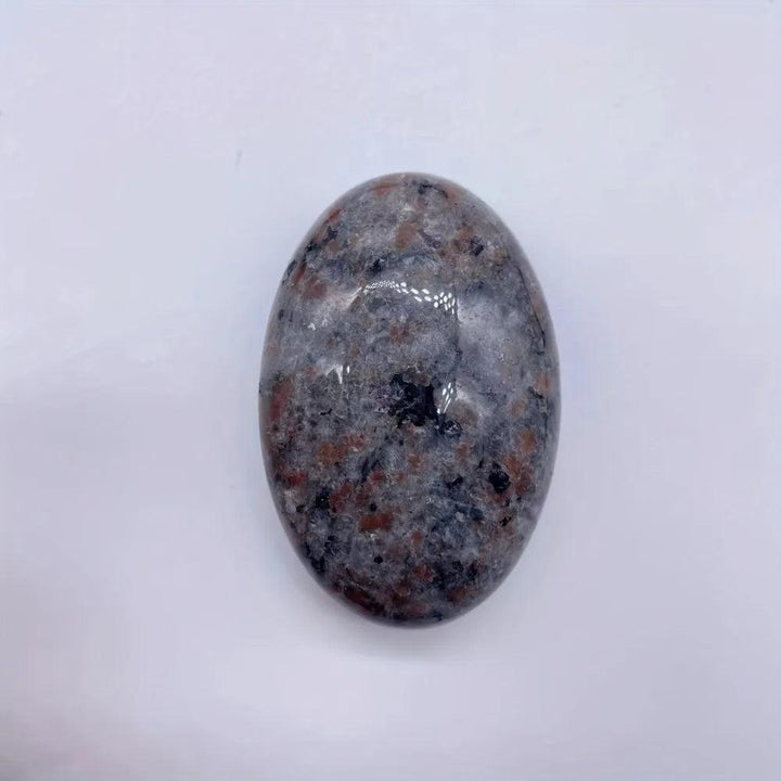 Yooperlite Crystal Palm Stone, a smooth, grounding grey stone with subtle flame-like patterning, for stability and protection.