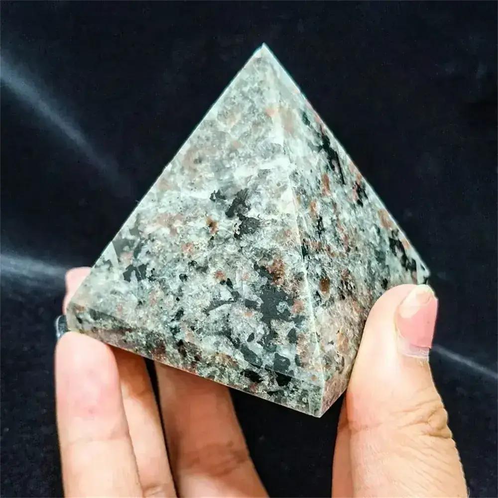 Hand holding a gray, black, and red speckled Yooperlite Crystal Destiny pyramid, amplifying intuition and creativity.