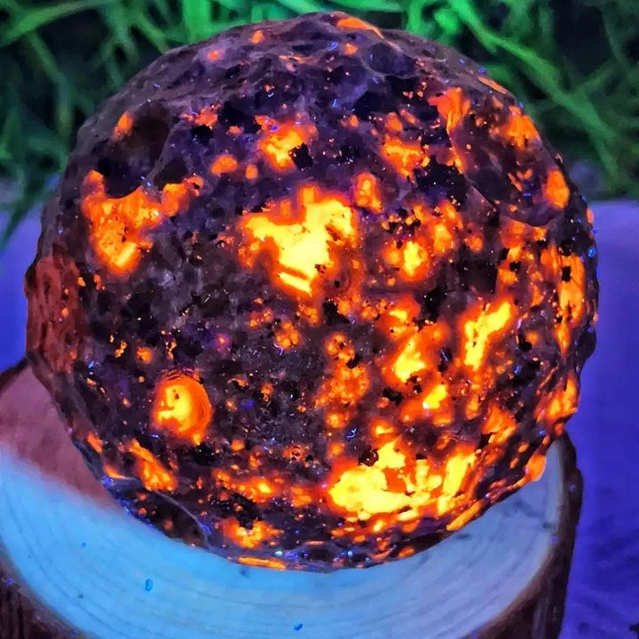Yooperlite Crystal Sphere UV Reactive Glowing Moon Ball, a dark sphere with blazing orange and gold flame-like patterns.