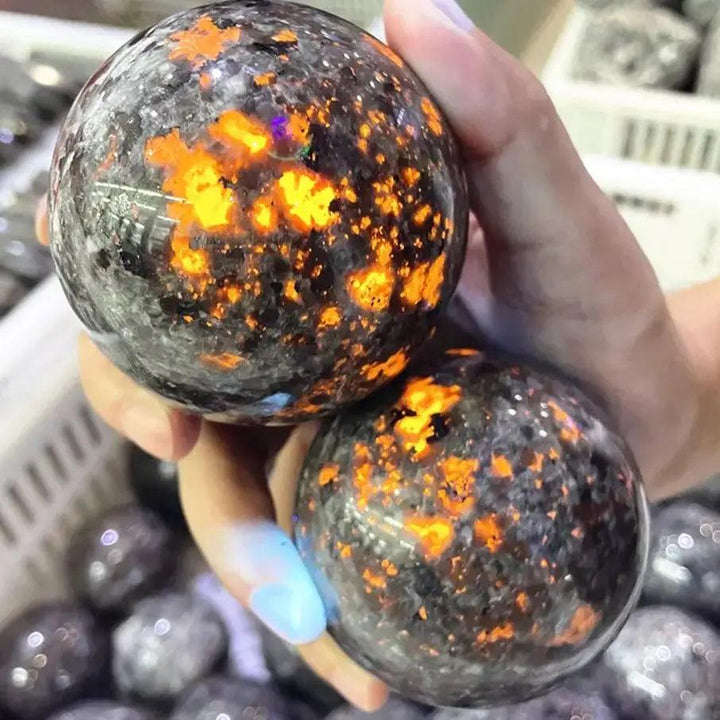 Polished Yooperlite crystal spheres glowing with vivid orange fluorescent sodalite under UV light for grounding energy.