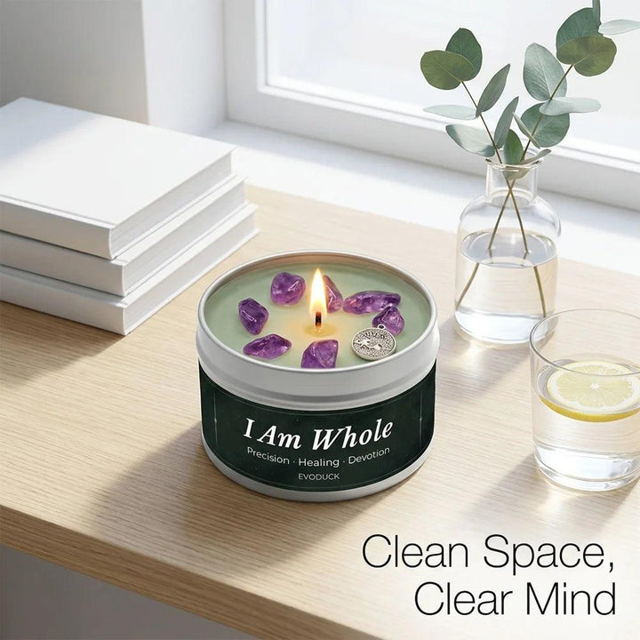 I Am Whole" Amethyst crystal-infused White Tea & Sage tin candle, burning on a light wood surface.